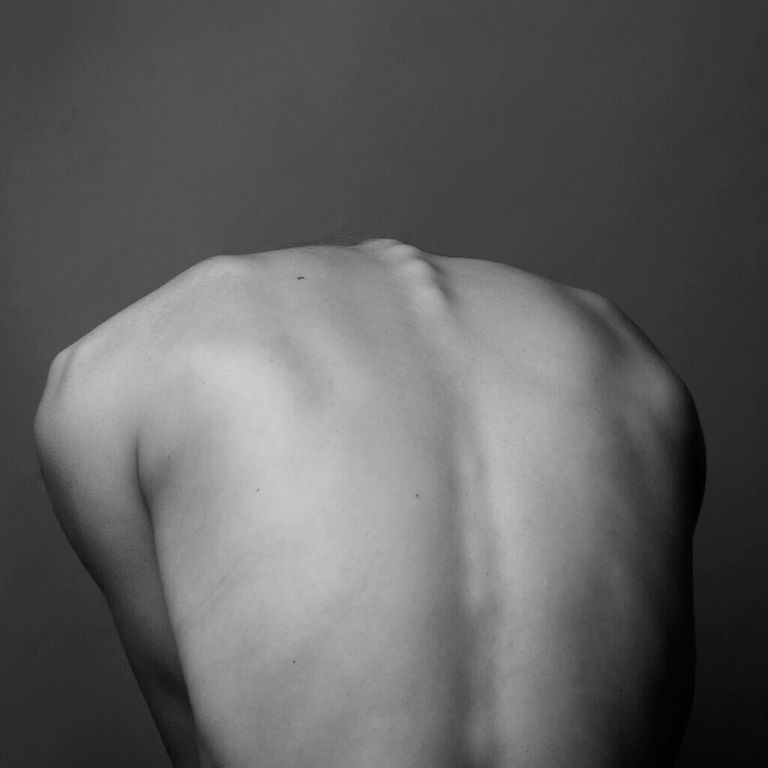 Dos nu d'un homme montrant sa colonne – réflexologie plantaire pour apaiser les douleurs lombaires et dorsales