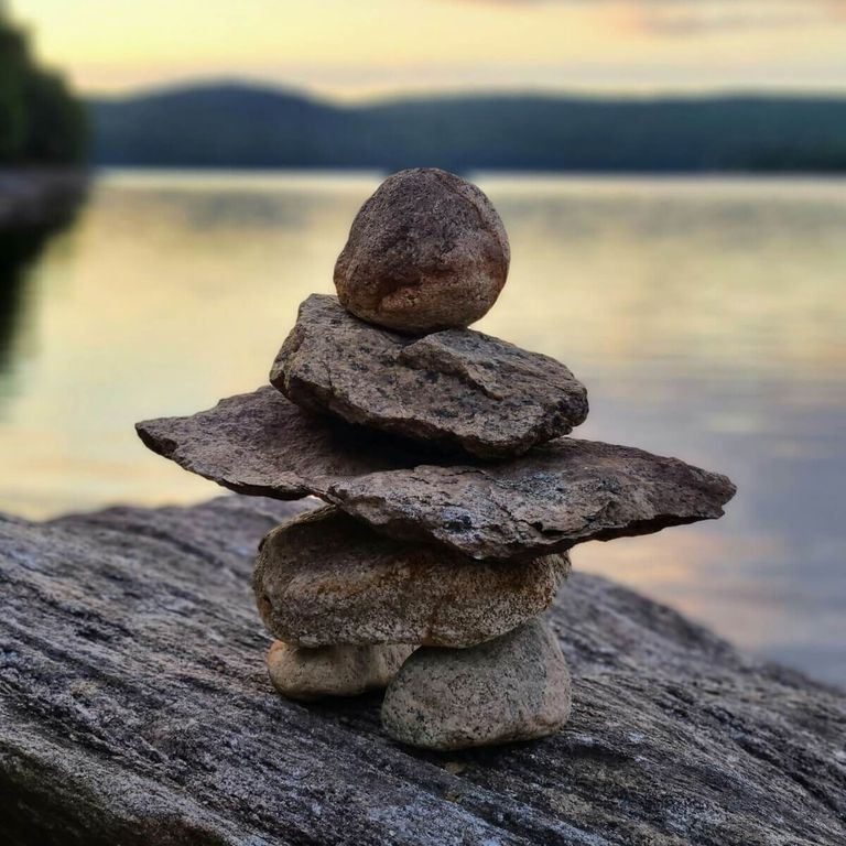 Galets empilés au bord de l’eau, symbole d’équilibre et d’harmonie, illustration de la réflexologie plantaire pour soulager les douleurs
