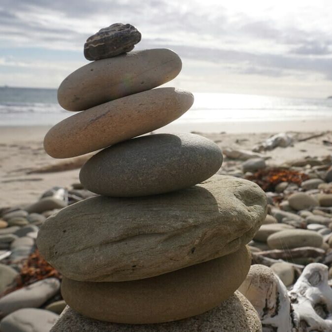 Galets en équilibre sur la plage – représentation du parcours Équilibre & Bien-être en réflexologie plantaire pour soulager les douleurs 