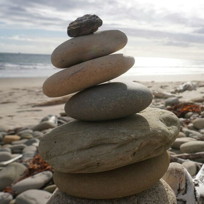 Pierres empilées sur une plage – symbole d’équilibre et de stabilité pour l’accompagnement Équilibre & Bien-être